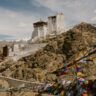 Stunning view of Namgyal Tsemo Monastery in the Himalayas with prayer flags waving in the wind.